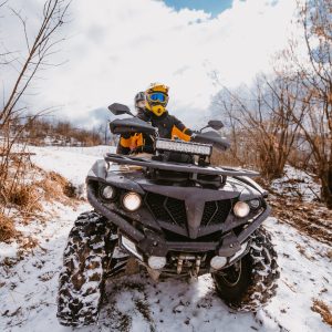 A young adventurous couple embraces the joy of love and thrill as they ride an ATV Quad through the snowy mountainous terrain